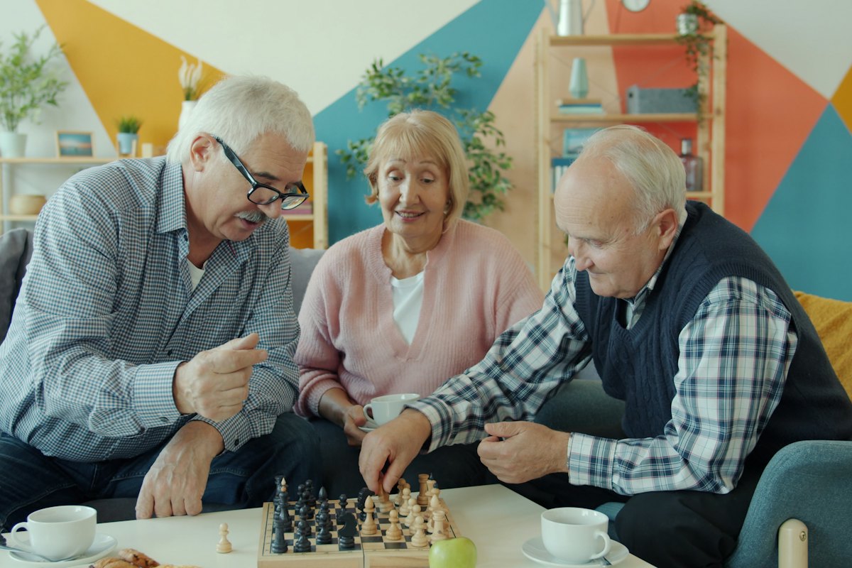 Three retirees playing chess together in a living room