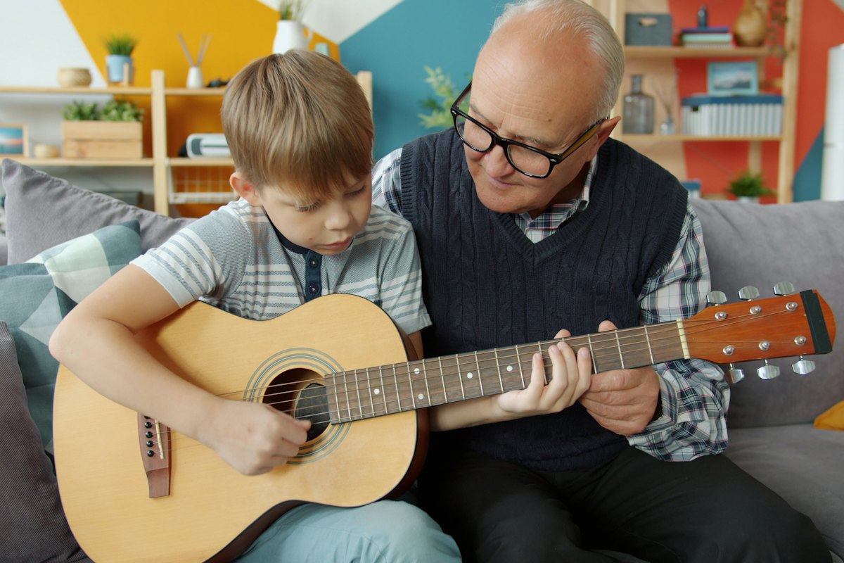 A grandfather teaching his grandson to play guitar
