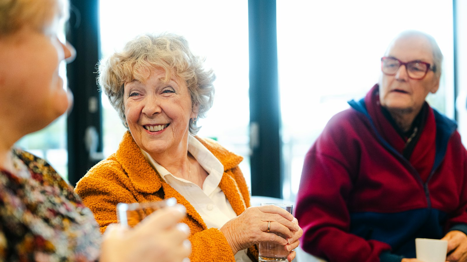 A group of retirees laughing and talking together over coffee