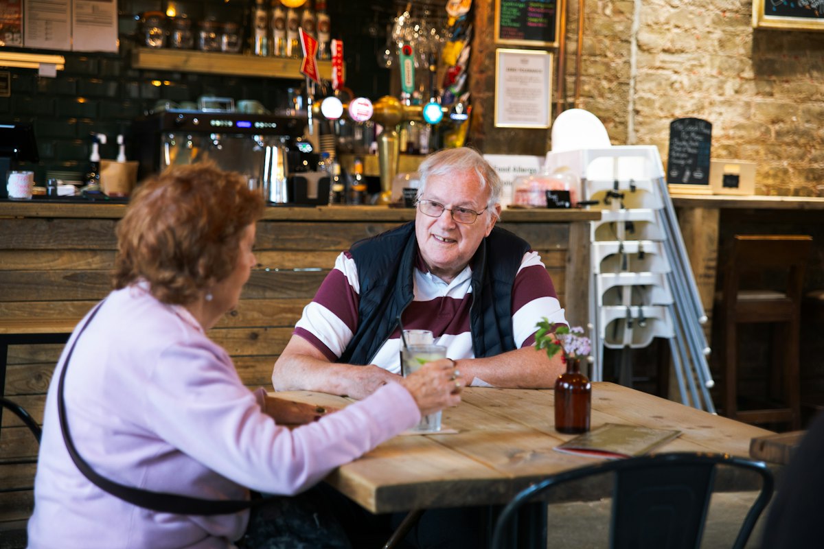 A retired couple talking over coffee at a café table