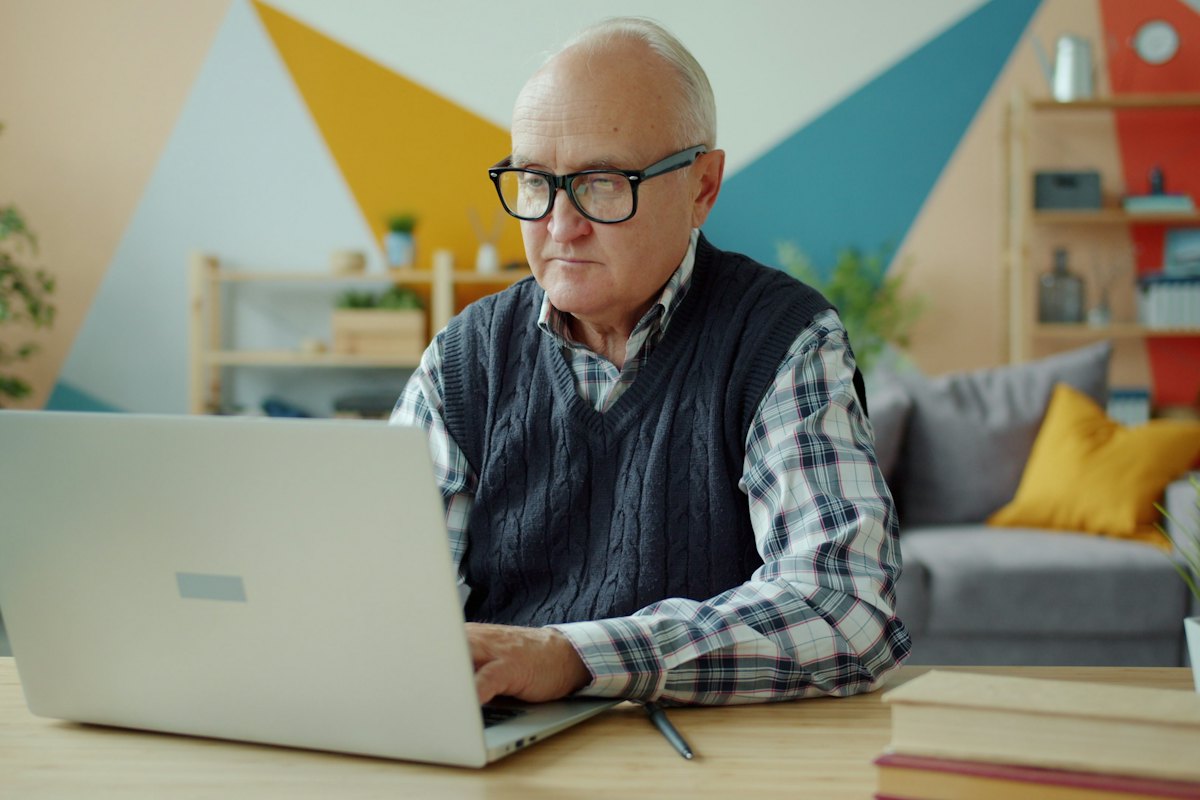 A retired man planning at his laptop at home